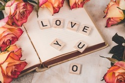A book with roses and the 'LOVE YOU' words made from wooden blocks