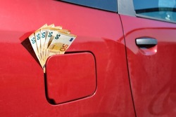 Fifty euro notes sticking out of a car's closed fuel tank, raising fuel price 