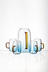 the Vertical shot of a glass blue transparent  cups and juice pot with a white background