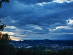 gloomy sky over city, panorama of a city at the Danube with dark sky, thunderclouds over suburban area, overcast
