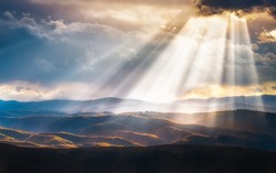 A scenic view of hills and mountains filled with evening sunrays