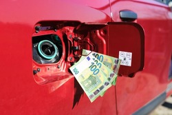 Three one hundred euro notes attached to an open fuel tank, symbol for rising fuel price 