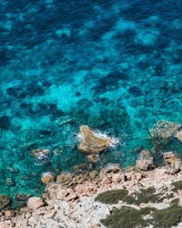 A vertical high angle shot of the vibrant clear blue waters at the Atlantis cove in Ibiza