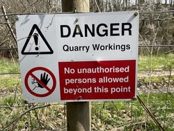 A Quarry danger, no unauthorized persons beyond this point sign fence post