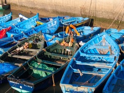 A number of old, blue boats on the port in Essaouira, Morocco in daylight