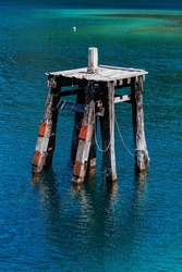 A vertical shot of a wooden mooring dolphin in turquoise water  on a sunny day