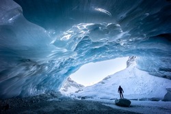 Silhouette of someone standing on a rock while exploring an ice cave in Zinal glacier, Valais Switzerland