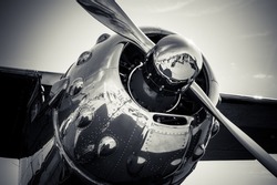 A grayscale close-up shot of a metallic aircraft propeller reflecting the environment 