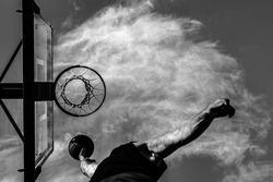 A grayscale shot of an airborne athlete about to shoot a basketball