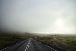 An asphalted countryside road under the misty sky