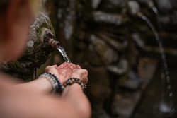 A closeup of hands under a holy fountain with sacred water in Goa Gajah Temple, Bali, Indonesia