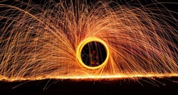 A dramatic glowing long exposure of  spinning light trails with sparks