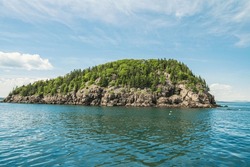An isolated cliff island covered with dense vegetation surrounded by a waterscape