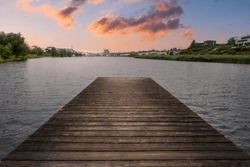A boardwalk leading to a scenic waterscape during a sunset