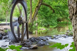 A closeup shot of a water wheel, spinning and directing water from a stream, through the wooden canal, to the water mill