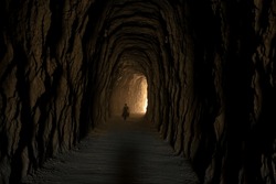 A view of a person crossing a deep cave tunnel