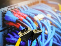 Both end of a VGA Cable (Male and Female) having nine pins In front of a network switch