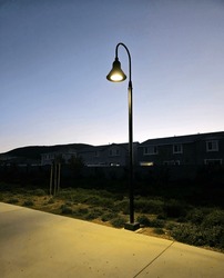This image depicts a suburban street lit up by a single street lamp at dusk