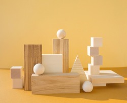 Geometric composition with many three-dimensional wooden figures on yellow background. Balance, art and design concept.