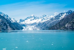 A distant view of Margerie Glacier, Alaska.  Icebergs from the glacier are floating on the water surface in the foreground and snow capped mountains in the background.  