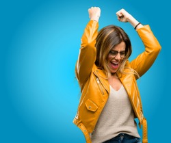 Beautiful young woman happy and excited expressing winning gesture. Successful and celebrating victory, triumphant, blue background