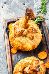 Chicken legs in pastry.Chicken leg in puff pastry on cutting board.Baked chicken drumsticks on cutting board
