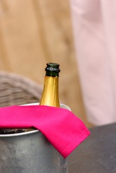 Iron winecooler without cork with a magenta serviette waiting for the guests to arrive against lightbrown wooden background