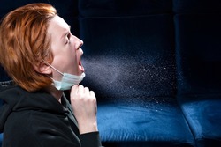 Influenza, cold, coronavirus. Infection through an airborne droplet. Girl with red hair in a medical mask coughs. A cloud of virus droplets in the air.