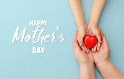 Concept Happy Mother's Day or International Day of Families.Happy women's day.Heart in the hands of daughter and mother on a blue background.I love you.Banner for store.Greeting card. Top view. Banner