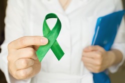 World bipolar day. Doctor in white coat holds green ribbon. Mental health awareness day, Depression, Cerebral palsy. World kidney day. banner. copy space.