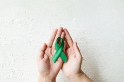 World Mental health awareness day. Woman hands holding green ribbon on white background. Depression, Cerebral palsy. World bipolar day. banner. copy space