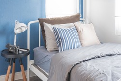 single white bed with white lamp and blue wall in kid's bedroom