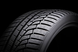 winter tire, driving safety on snowy and icy roads. asymmetric tread pattern. close-up on a black background.