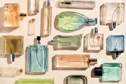 perfume bottles. a lot of transparent multicolored glass bottles of cosmetics, on a beige background. art composition flat lay still life