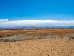 Agafay Desert with deep blue sky and low bank of white clouds with copy space.