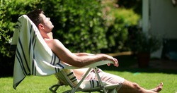 
Man sunbathing outside in home lawn. Person outdoors relaxing
