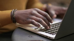 Close-up black african man hands typing on laptop computer