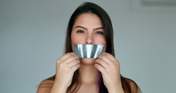 Assertive woman removing tape from mouth feeling relief and freedom to speak