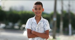 Brazilian child smiling at camera outside in street. Hispanic south american kid boy