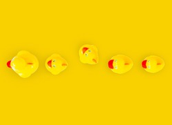 A row of yellow rubber ducks with one of the ducks facing in a different direction all the other duck are facing. 