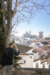 Granada old town and the Cathedral. Man is taking a photo with his smartphone of the Granada's views. It's a sunny day in Granada, Andalusia, Spain.