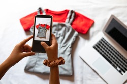 Woman taking a photo of an article of clothing to sell online. Concept of selling clothes online. Second-hand clothes.