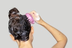 hair growth stimulating, scalp massage.woman using  pink scalp massager shampoo brush with silicone,flexible bristels.hair care,head relaxation.shampoo foam on hair,hand,isolated