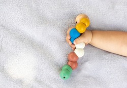wooden toy caterpillar and cute baby boy sitting,lying outside on picnic blanket.park,garden environment,sunny summer day.toddler puts in mouth eco wooden colorful  worm toy.fine motor skills