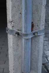 Wide aluminum metal clamp on concrete column with large metal steel bolts, concrete structure, concrete column reinforcement