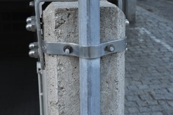Wide aluminum metal clamp on concrete column with large metal steel bolts, concrete structure, concrete column reinforcement