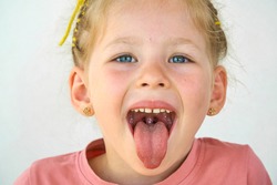 Cheerful smile child. Girl laughs close-up of the face on a white background. little girl show tongue, throat. portrait with wide open mouth and protruding tongue. clear view pulls out long tongue. 