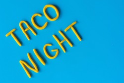 The words TACO NIGHT are made of clay on a blue background, flat lay. USA, Mexican holiday, background with text.