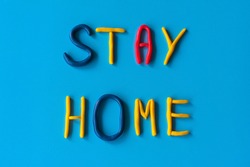 Stay home words from letters made of clay on a blue background, flat lay, background with text.