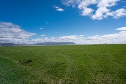 green open fields  in the country side with blue sky and mountains in distance